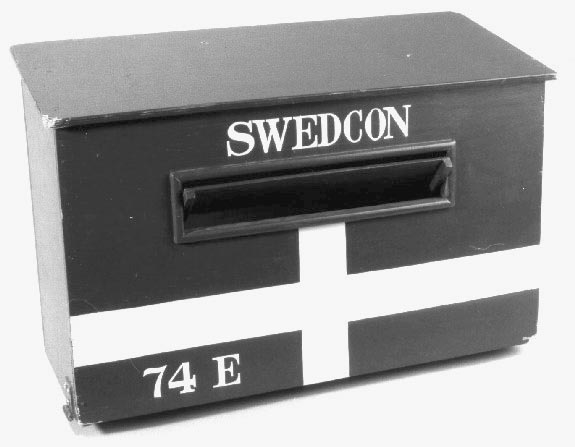 Brevlåda i trä med klaff för iläggsöppningen.
Iläggsöppningenhar mått:L=330 mm, H=40 mm. På fronten är lådan målad som den svenskaflaggan. Tömningslucka i botten, låsbar med hänglås.