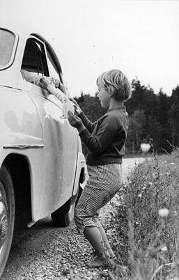Lilla Ulrika Hellström, 5 år, som semestrar i Eskelhem, får hälsningar från sina lekkamrater hemma i Stockholm av fru Astrid Friborg, bilåkande lantbrevbärare, på linjen Klintehamn - Västergarn - Klintehamn. Foton 10 - 11 augusti 1964.