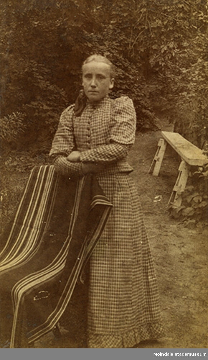 Helfigursporträtt av en stående kvinna, taget utomhus, cirka 1890.
Namnet Alida Olsson är skrivet på baksidan av fotot.