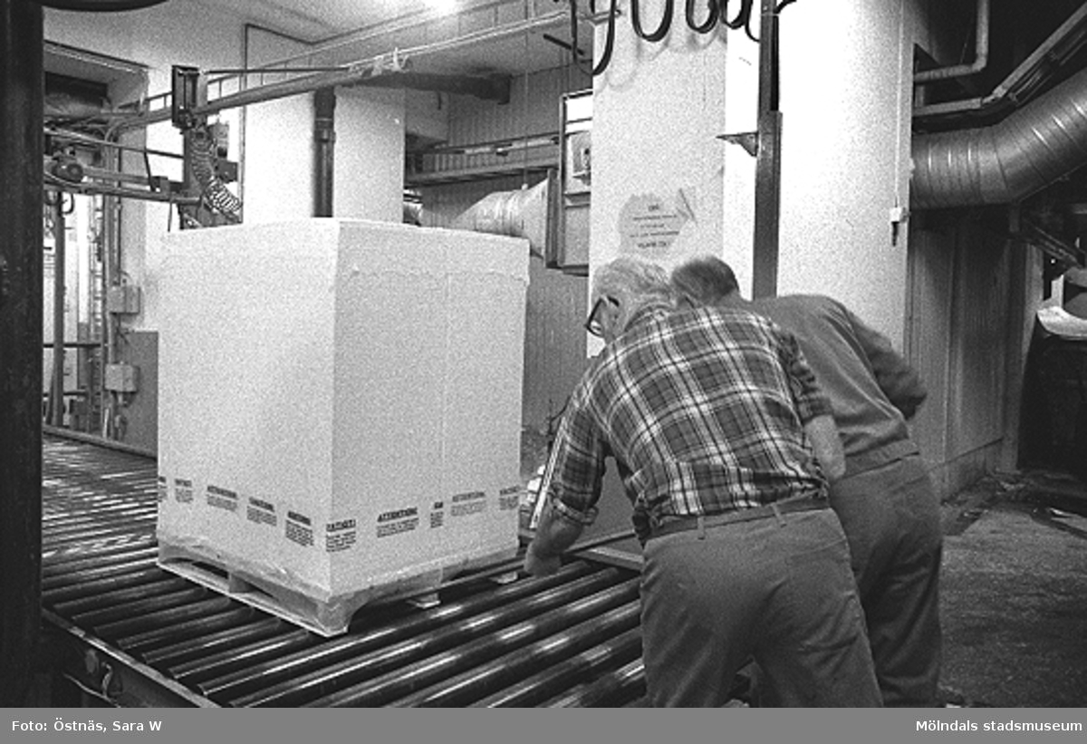 Från vänster: Gotthard Olsson och troligen Tage Carlsson arbetar med pallpackning i pappersfabriken, Byggnad 6. Bilden ingår i serie från produktion och interiör på pappersindustrin Papyrus, 1980-tal.