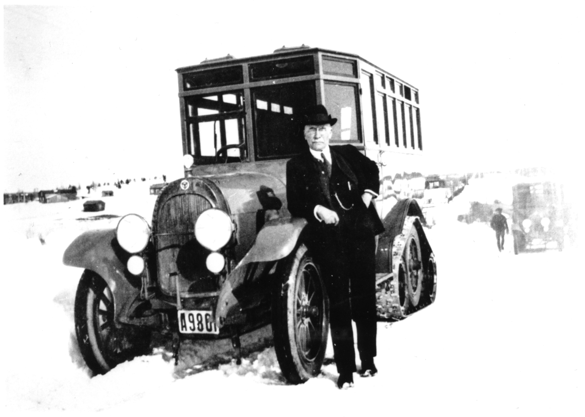 De första postdiligenserna utvecklades 1922-23 genom ett samarbete
mellan Scania-Vabis (chassie) och Postens Verkstäder i Ulvsunda
(karosseri). Observera banddrivningen på bakhjulen för bättre
framkomlighet i snö. Mannen framför vagnen är Postens dåvarande
generaldirektör Julius Juhlin.