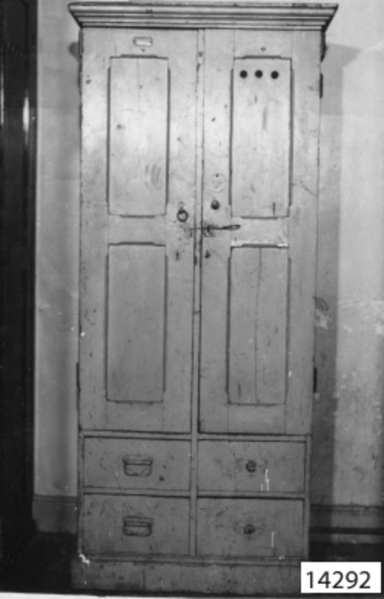 Skåp dubbelt av furuträ. Skåpet är gråmålat och har två dörrar samt under dessa fyra st lådor. På skåpet är Johanssons gamla närvarobricka fastskruvad. Brickan rund och märkt 2360
56.
