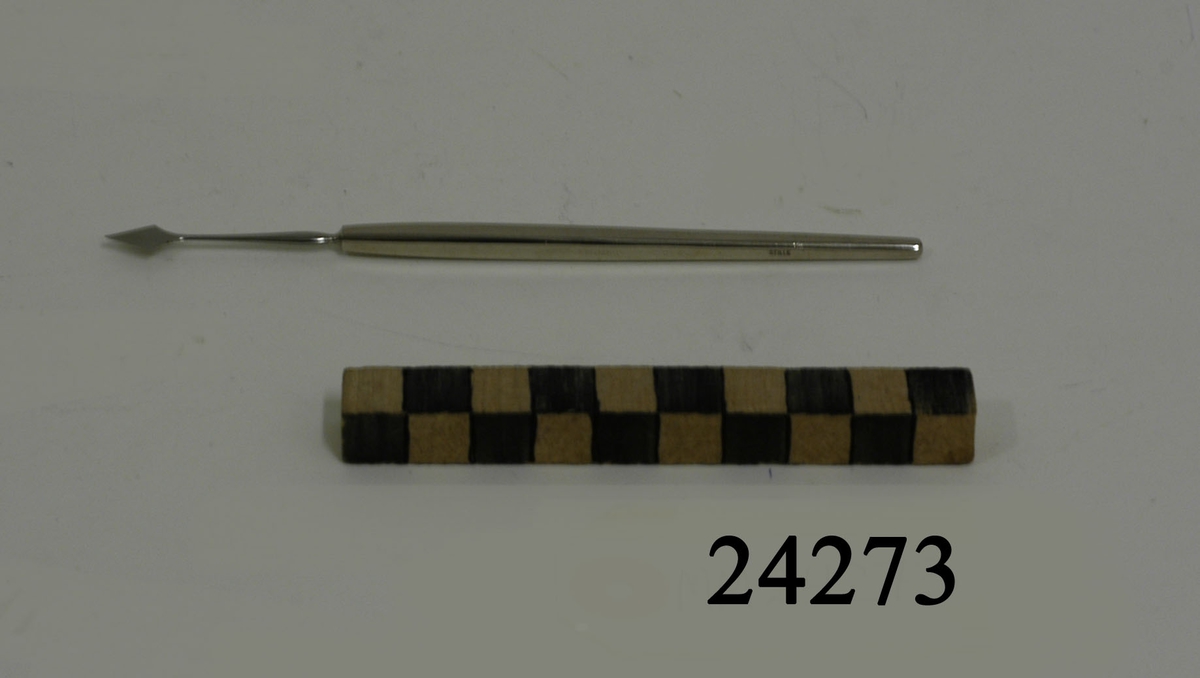 Tunn, rak, platt lansettformad operationskniv av rostfritt stål. Tveeggat knivblad. Blankt fyrkantigt skaft. Text i godset: "STILLE".