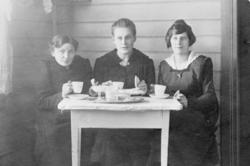 Tre kvinner rundt et bord, kaffeselskap.