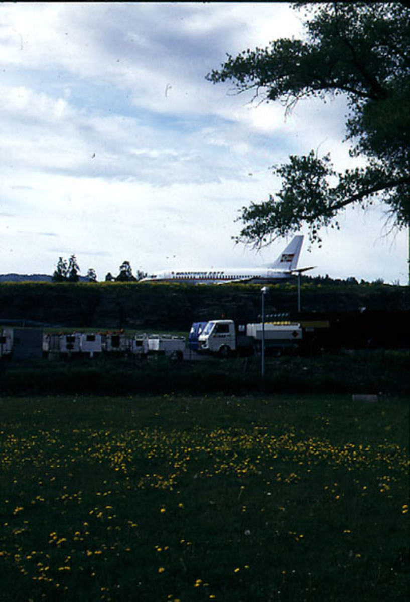 Lufthavn, 1 fly på bakken, LN-BRN Boeing 737 500 "Håkon Herdebrei" fra Braathens Safe". Flere kjøretøy på bakken nedenfor flyet, i forgrunnen.