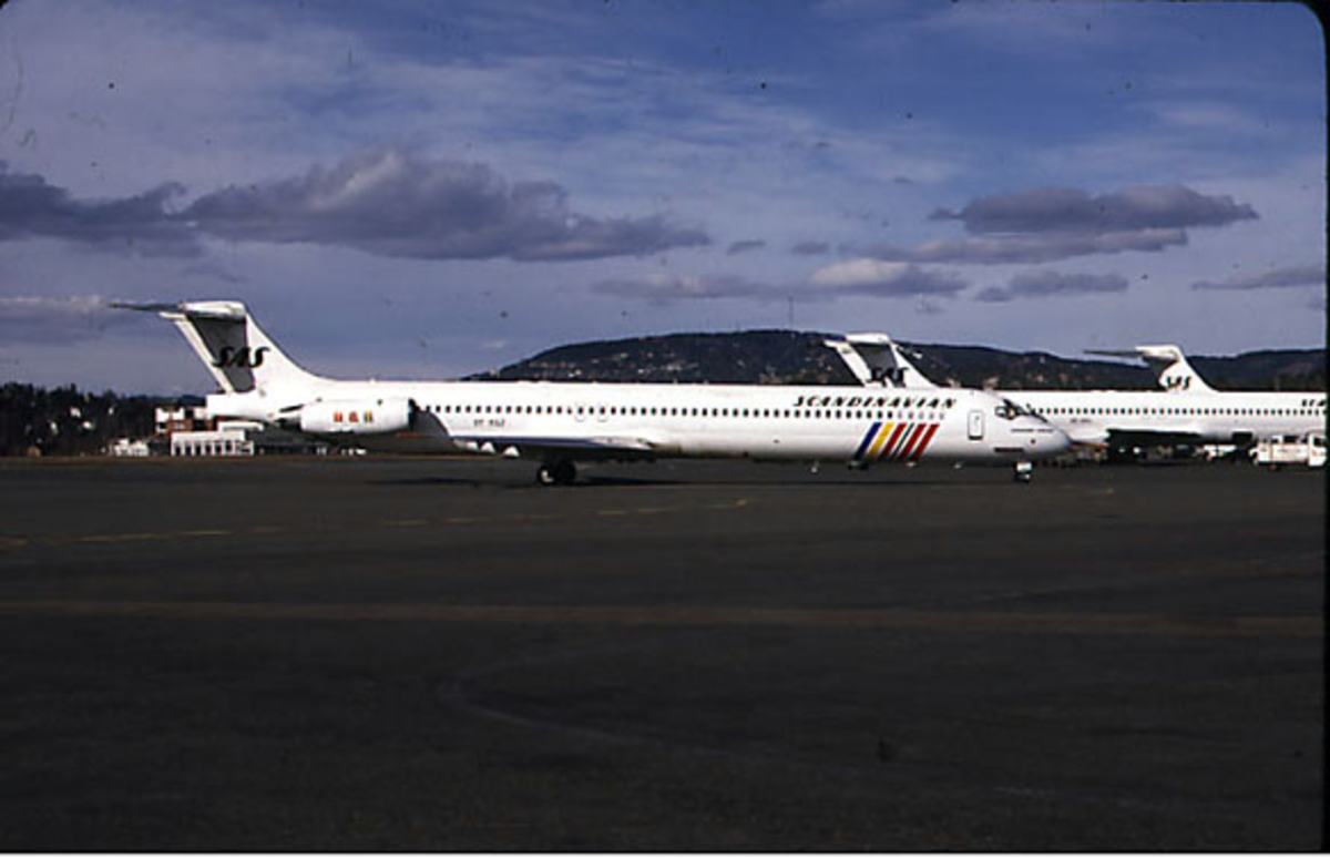 Lufthavn. Flere fly parkert på rullebanen. I forgrunnen MD-81 OY-KGZ  "Hagbard Viking" fra SAS, sett fra siden. 