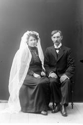 Brudepar studiofotografert i helfigur foran ensfarget baktep