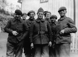 Gruppebilde av franske eller polske soldater foran en husveg