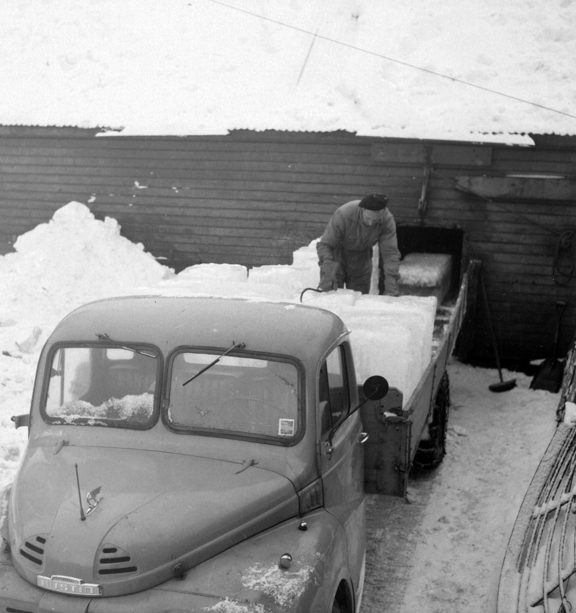 Isskjæring på Møkkelandsvannet, 1954. Her laster Asbjørn Berg, Kilbotn, isblokkene på lastebil før transport til kaia hos Bertheus Nilsen i byen.