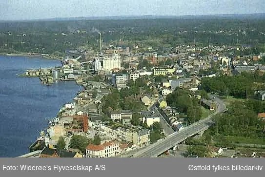 Oversiktsbilde og flyfoto over Sundbryggene og  Moss sentrum i 1964.
Bildet viser tydelig  omfanget av bygninger som måtte rives for å realisere Rådhusbrua tidlig på 1960-tallet.