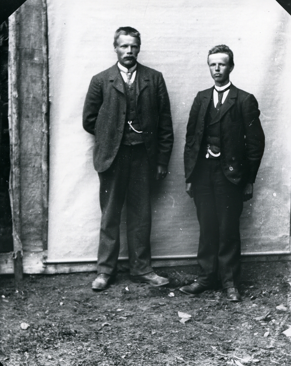 To dresskledde menn, stående foran lerret