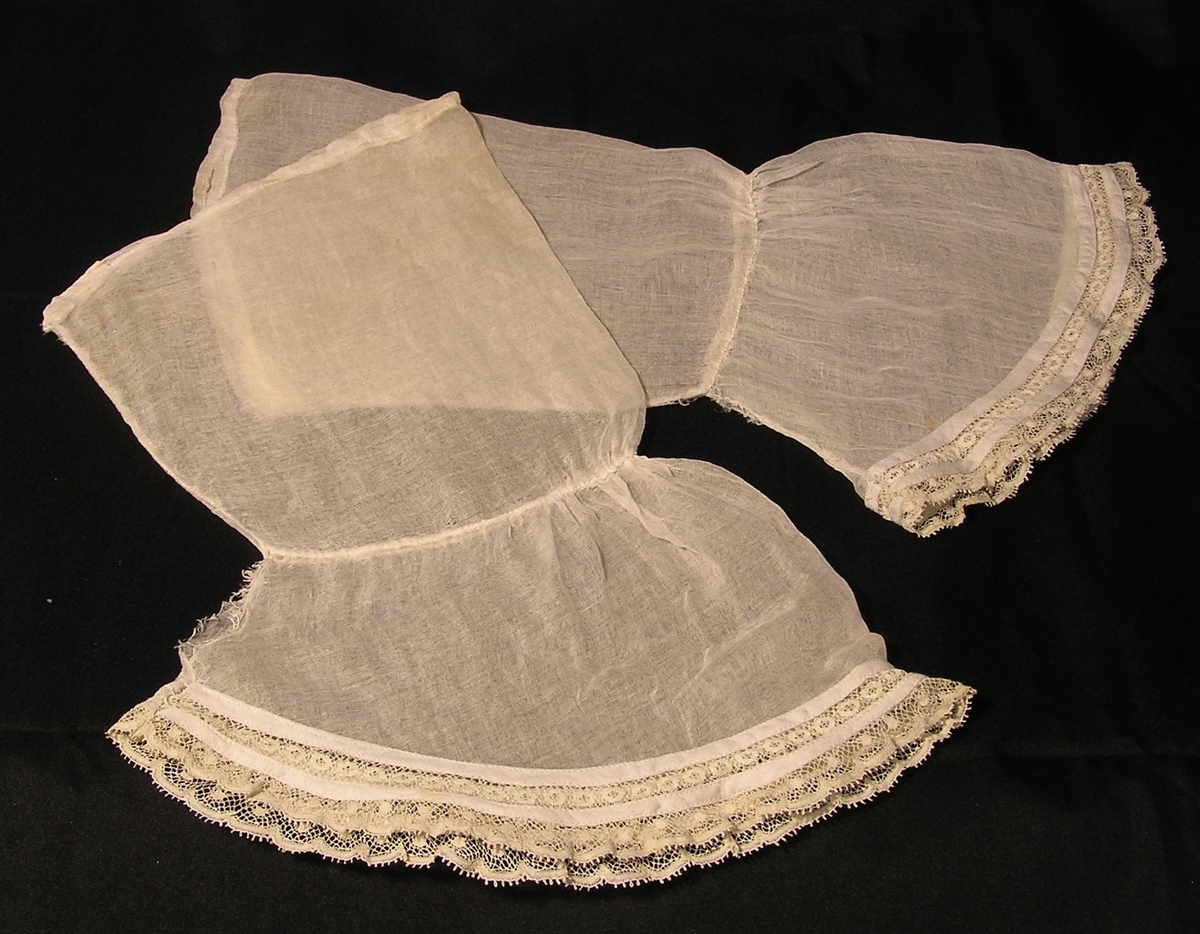 Maskinblonde påsydd med 1-tråds symaskin. Øvre del en søm. Ttilsydd mansjett, rynket på oversiden.