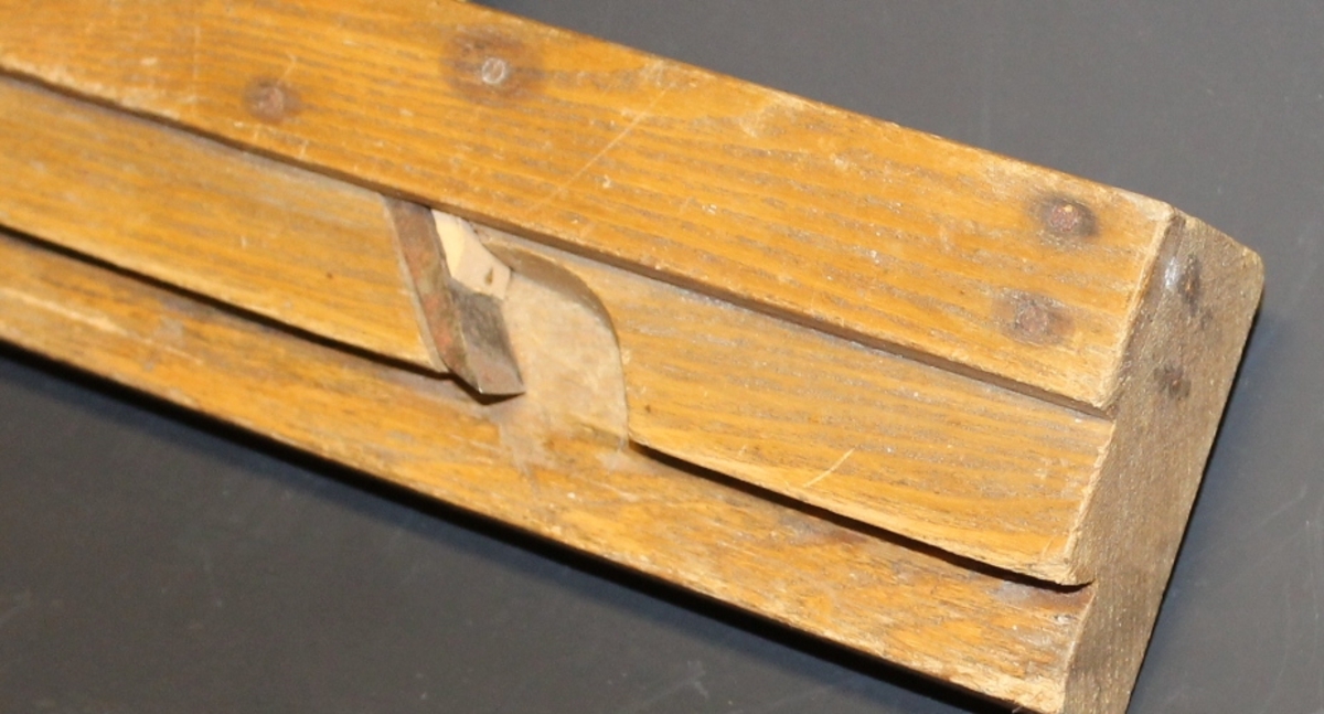 Form: smal, høy høvelstokk med høveljern og kile; sponhus i siden, profilsåle