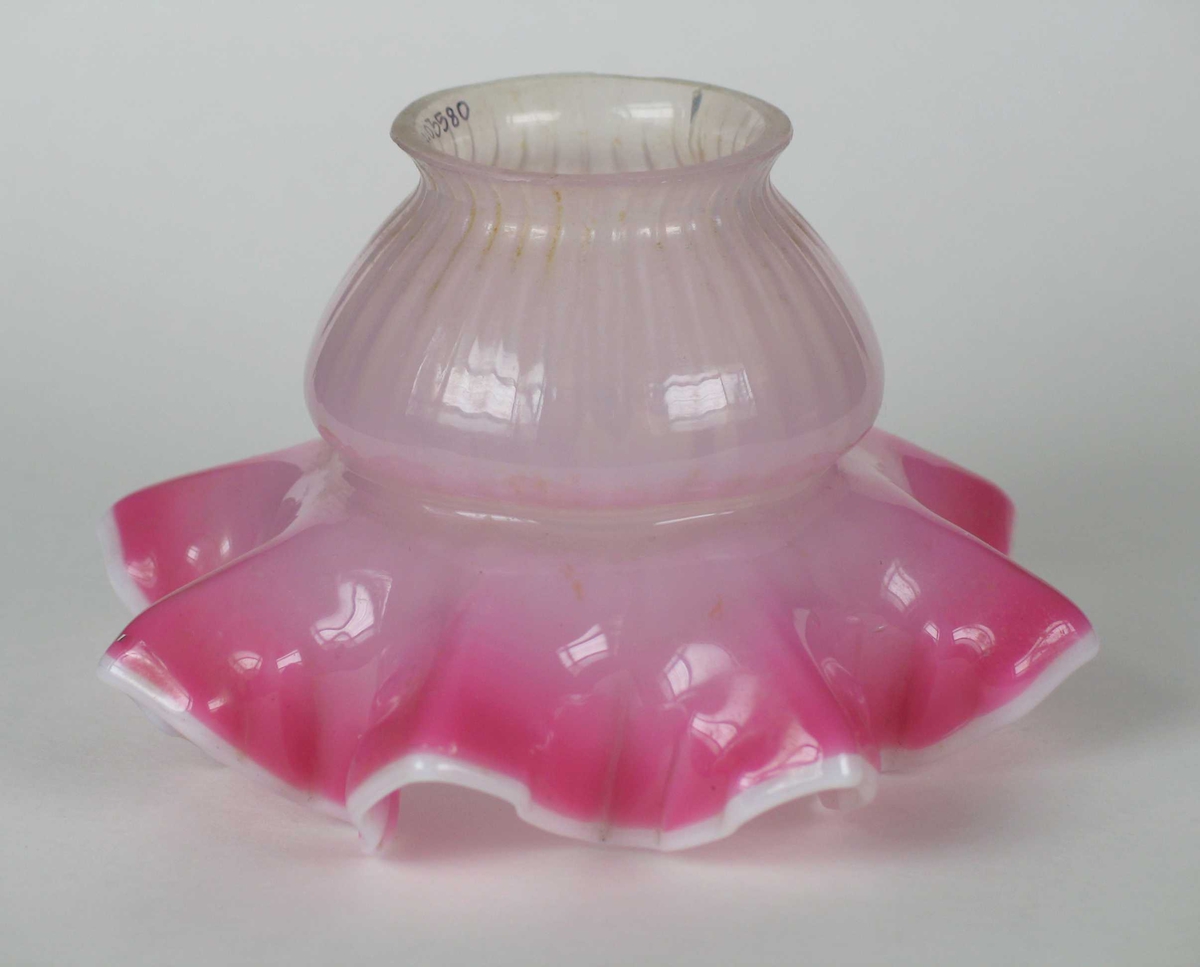 Rosa lampeskjerm i glass med bølget kant nederst.