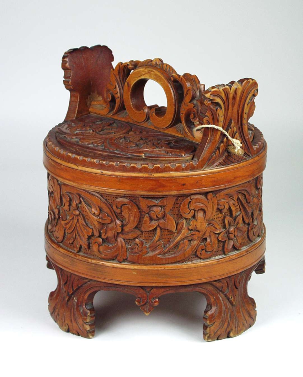 Ambaren er lagget av åtte staver. Fire staver er forlenget til bein og to til ører. Beina og ørene skrår utover. To flate gjorder. Lokket er laget av ett stykke påsatt håndtak. Beina og ørene er dekorert med akantuspalmetter. Rundt ambaren går en akantusranke i forholdsvis høyt relieff på prikket bunn. I hver buktning på ranken er det satt inn fire-, fem- eller seksbladete blomster. En sett fra siden og resten ovenfra. Ranken har kraftig smetting av bladene fra sideskuddene. Ambaren er lakket. Lokket har tilsvarende akantusskurd som ambaren, med fire fembladete blomster. På lokket har også noen av bladene lansettform med tagger.Håndtaket har gjennombrutt akantusskurd i rundskurd. Enkel låsepinne.
Ambaren er tidligere katalogisert som laget av einetre.