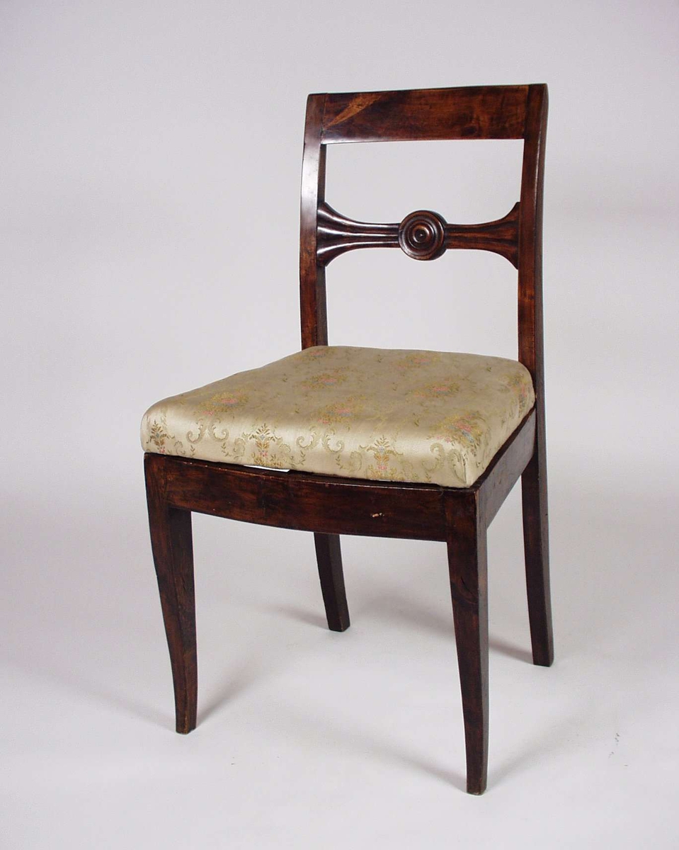 Stolen er av tre med løst sete som er trukket i tekstil. Stolens tverrspross er utskåret. Setetrekket er av nyere dato. Stilen er sen-empire.