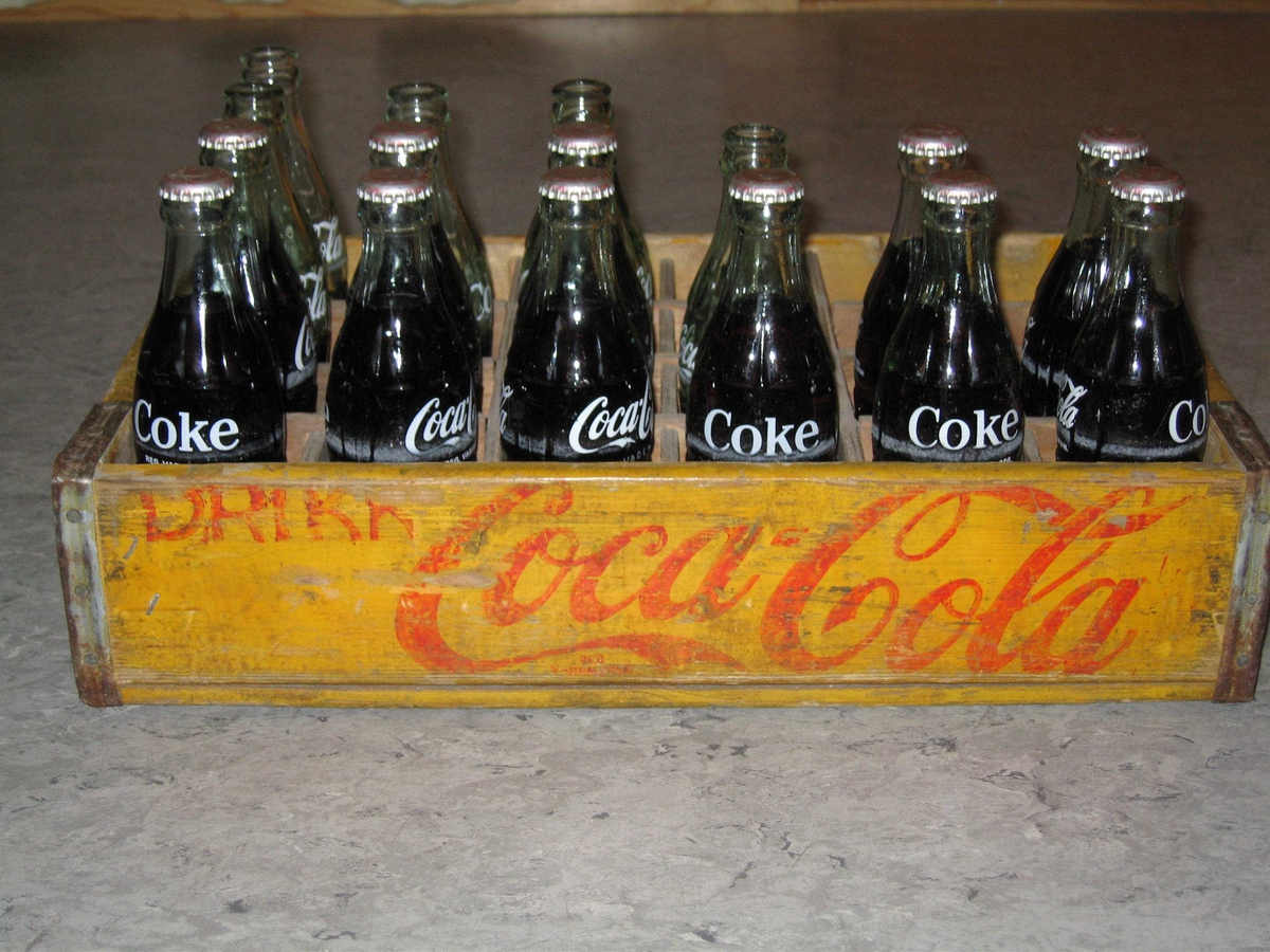 Trekasse til små colaflasker. Kassen inneholder 11 flasker med innhold og 5 uten.