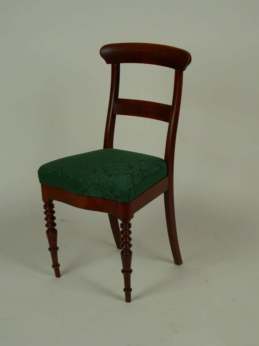 Brunbeiset stol med stoppet sete. Stoffet i setet er grønt.  Stilen er en blanding av biedermeier og historisme.