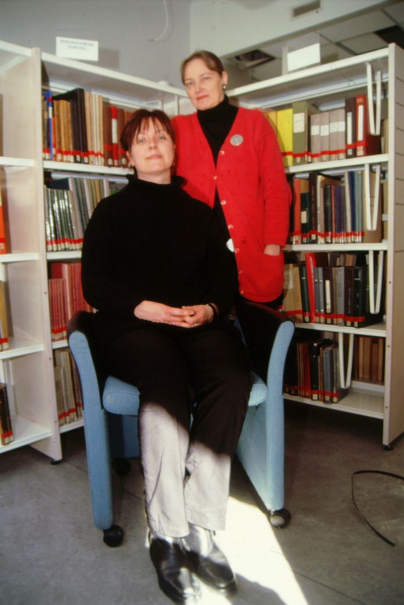 postmuseet, Kirkegata 20, biblioteket, Elin Eskerud sitter og Torgunn Haugaard står foran bokhyllene, stol