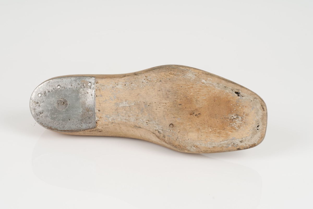 En tremodell i to deler; lest og opplest/overlest (kile).
Høyrefot i skostørrelse 38, og 8 cm i vidde.
Hælstykket i metall.