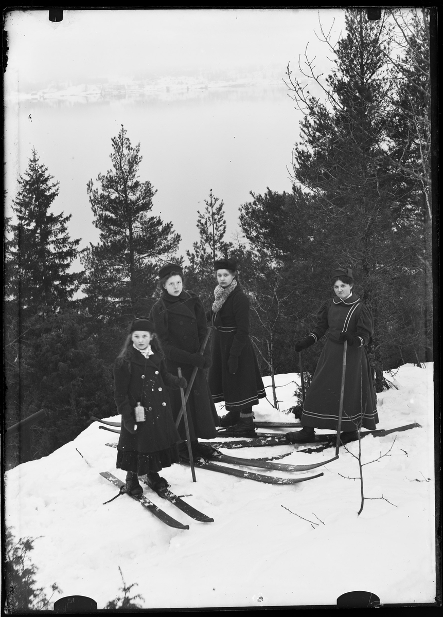 Kvinner i skidrakter på ski i skogen.