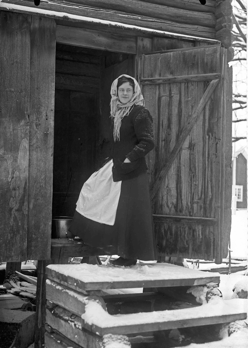 Kvinne som står i døra til stabburet.