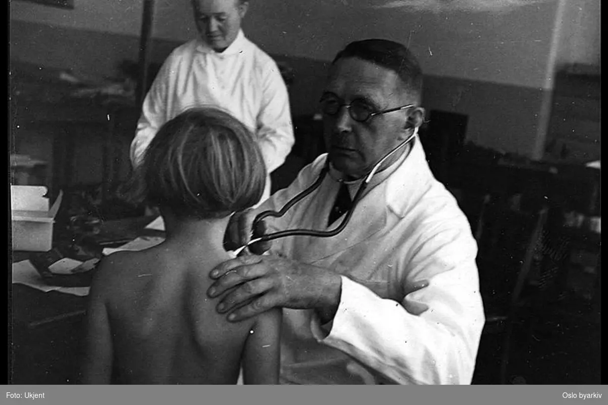 Skolelegen undersøker en pike. Helsesøster i bakgrunnen. Albumtittel: "Sofienberg skole femti år - første september 1933."