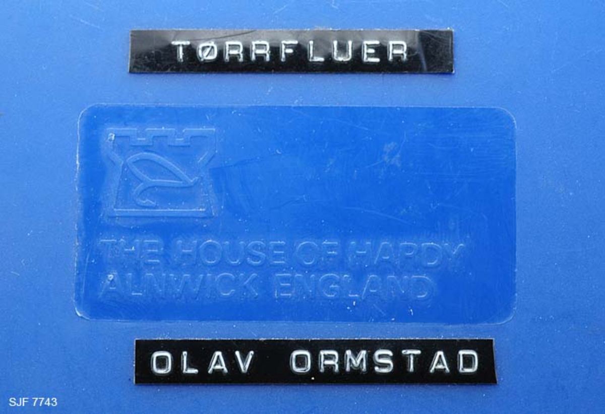 Tilstand: I forbindelse med omfotografering av gjenstander høsten 2002, oppdaget OT Ljøstad at fluene i denne esken var langt på veg ødelagte av møllangrep.  Problemet skyldes at gjenstanden har vært lagret i magasin C, der temperaturen er såpass høy at møllen trives. 
Boksen inneholder ialt 75 stk tørrfluer. Tørrfluene har den funksjon at de flyter på vannet, derfor så bustete. En meget fin boks som en setter fluene fast i, istedenfor at de ligger hulter i bulter. Giveren har skrevet ei bok med navnet "Isfiske" sammen med Knut Rom, boka ble utgitt i 1972. Giverens far var en ivrig sportsfisker og ble gitt tittelen "Den fullendte sportsfisker". 

Boksen inneholder ialt 75 stk tørrfluer. Tørrfluene har den funksjon at de flyter på vannet, derfor så bustete. En meget fin boks som en setter fluene fast i, istedenfor at de ligger hulter i bulter. Giveren har skrevet ei bok med navnet "Isfiske" sammen med Knut Rom, boka ble utgitt i 1972. Giverens far var en ivrig sportsfisker og ble gitt tittelen "Den fullendte sportsfisker". 
