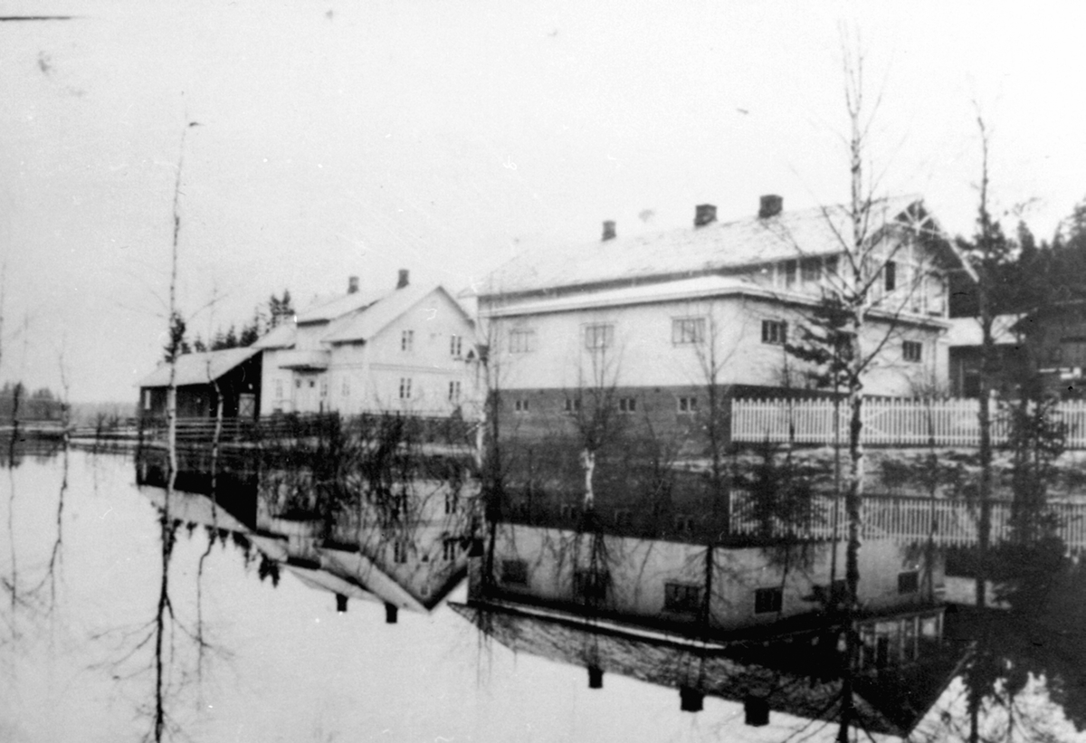 Eksteriør. Handelstedet Fagernes. Harby Landhandleri, Næroset, Ringsaker. Vårflom i 1938. Ny kafebygning med hybel for handelsbetjent og til overnatting for hestekjørere oppført i 1934. Butikken til høyre.