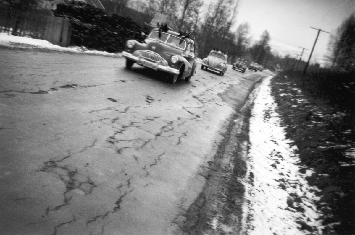 Brumunddal, Furnesvegen, "Sjåsjeen" lokal variant av fransk Chausse. Bildet er tatt nedenfor Mørkvedjordet med Konglehol i bakgrunnen. Påsketrafikk. Biler med ski på taket. Bilkø, første bilen er en Buick 1946-48.