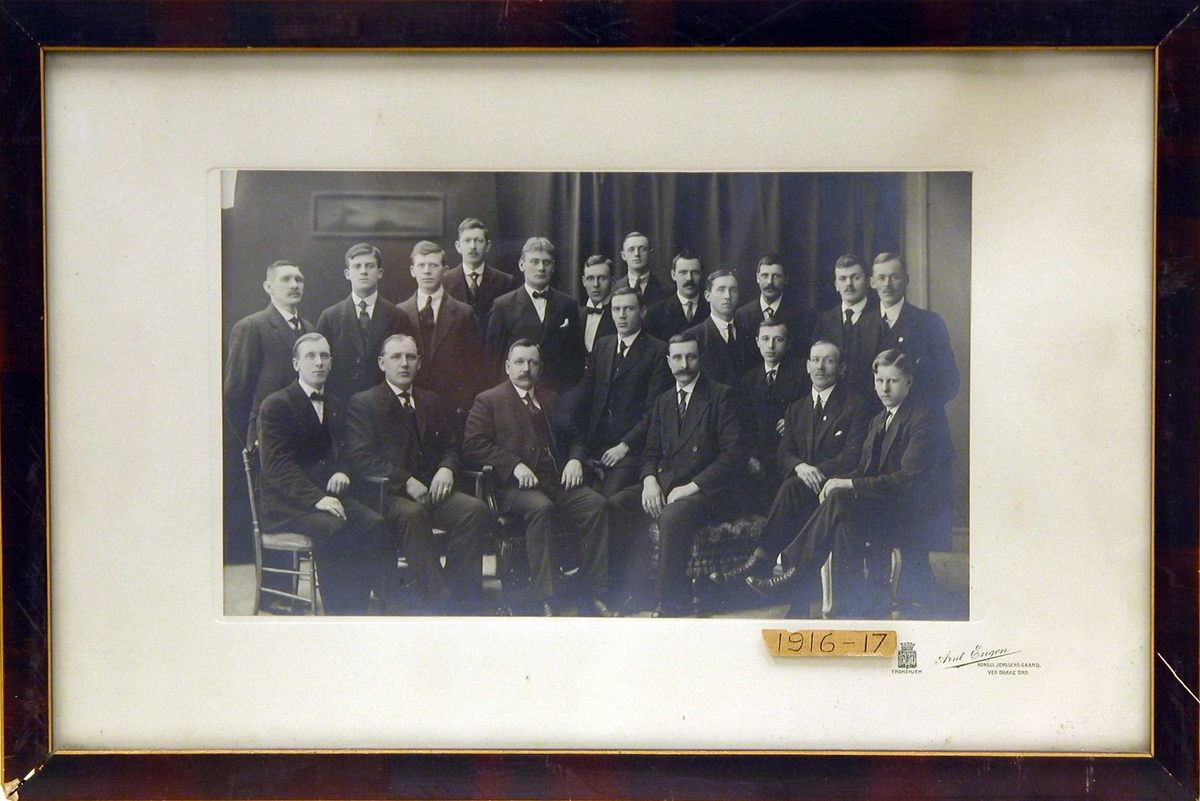 Klassebilde av 20 menn i dress.          Skipsførerklasse 1916-17. 13 stående, 7 sittende