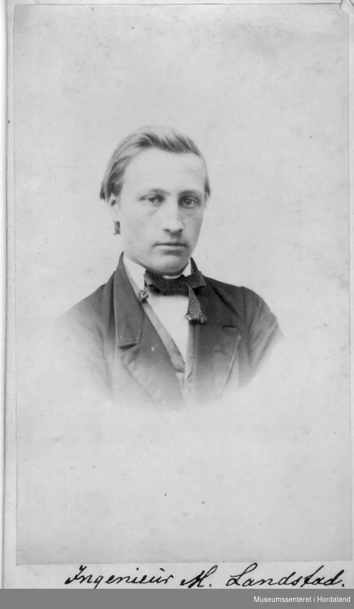 Portrett av mann med kort hår, dress med  vest, kvit skjort og sløyfe.