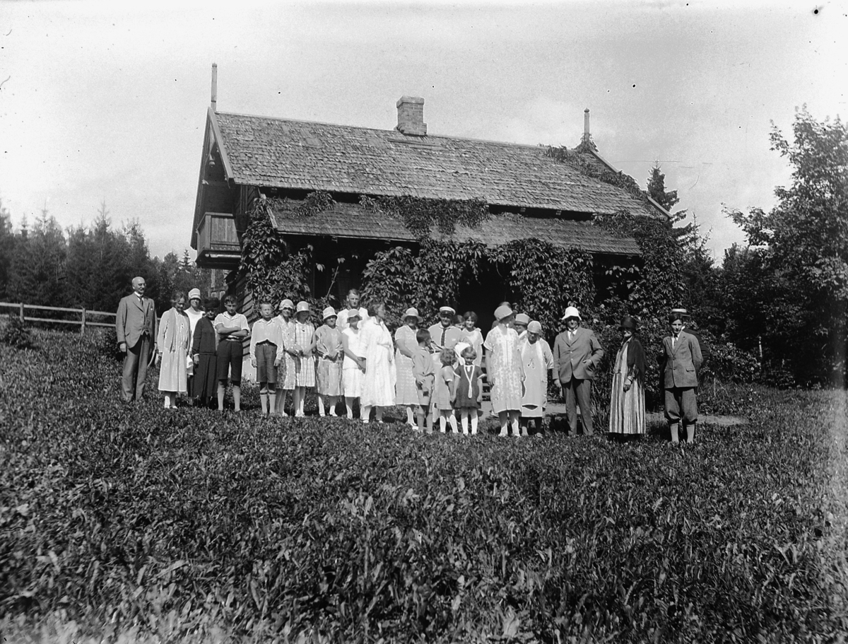 Gruppebilde foran hus. Selskap i Kvalstua, Helgøya. 
