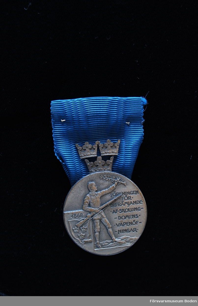 Tavla med uppsatta medaljer på svart sammet. Har tillhört Karl Hjalmar Lindskog, finlandsfrivillig 1939-1940. Från vänster på bilden:
1. Vinterkrigets minnesmedalj med svärd och spänne, Lappi, järn. Urkund finns i pärm under FMB.002361.
2. Frihetsmedaljen 2.klass, brons, urkund finns i pärm under FMB.002361.
3. Medalj från Föreningen för skolungdomens vapenövningar, silver.
4. Svärdstecken.
Överst på tavlan ett släpspänne för dessa medaljer.