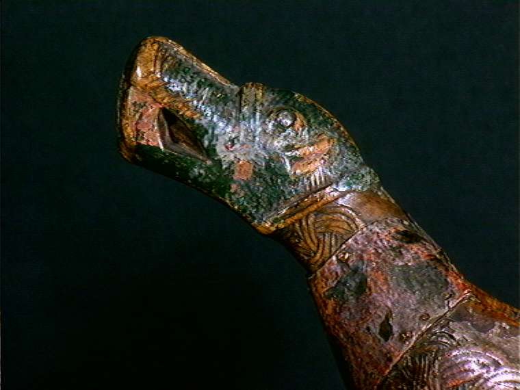 Bolle med håndtak formet som dragehovden. Flatskurd dekor: Geoometrisk bånd. Polykrom maling i flere lag.