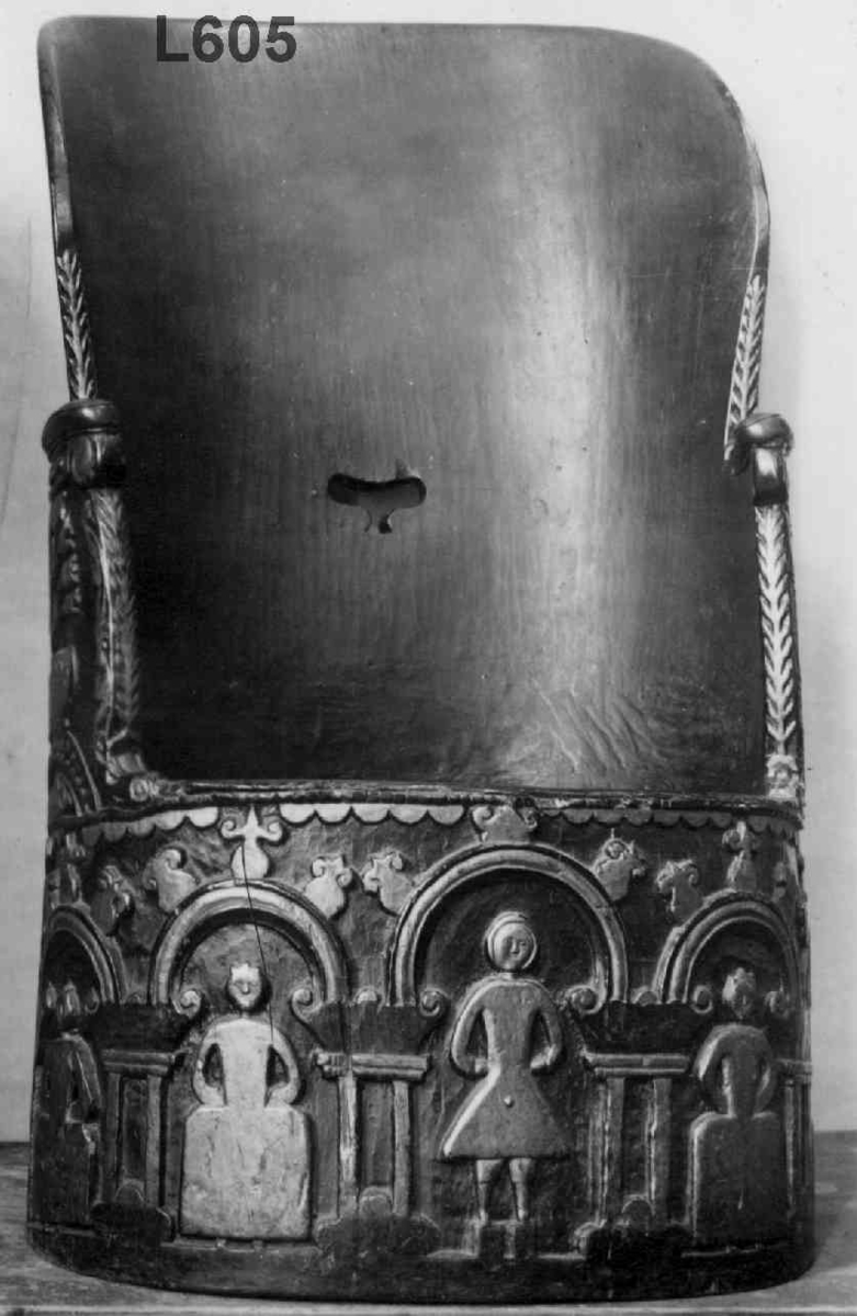 Kubbestol med skåret ornamentikk i form av menneskefigurer og blomster. Spår av maling.