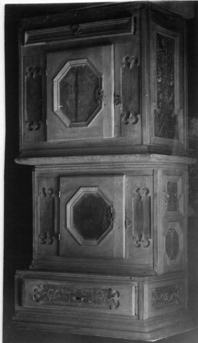 Rektangulært skap med to dører og to skuffer. Fyllinger er malt med blomstermotiv og rnaker. Innskrift AN 1795. Jernbeslag.  2 skaprom med hylle.