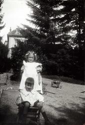 Dobbeltportrett, Sveits. Jente og gutt  i lek med trevogner.