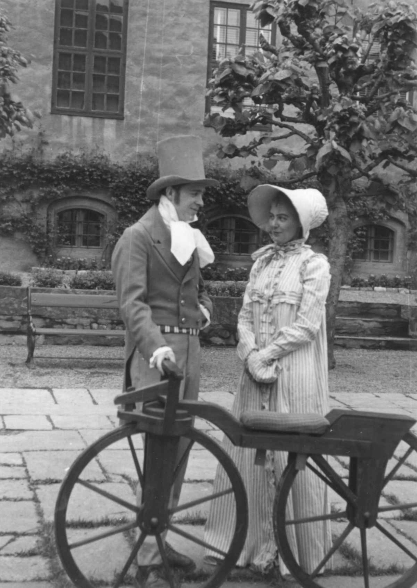 Sykkelkavalkaden i 1953. Mann og kvinne i tidsriktig drakt står med en sykkel fra ca. 1830.